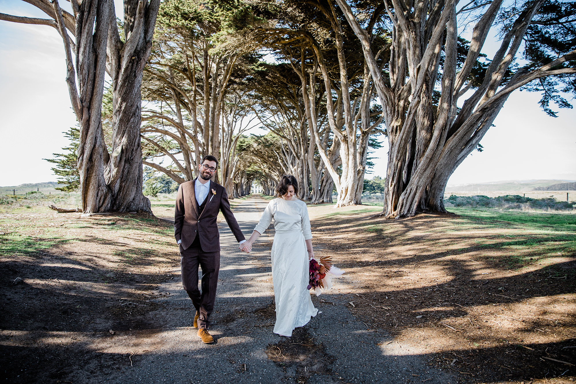 Bride and groom holding holds at the Cypress Tree Tunnel for Point Reyes Elopement.
