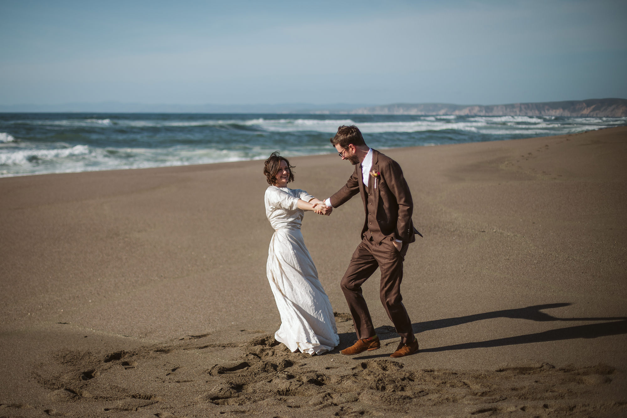 Bride and groom playing on the beach in Point Reyes elopement.