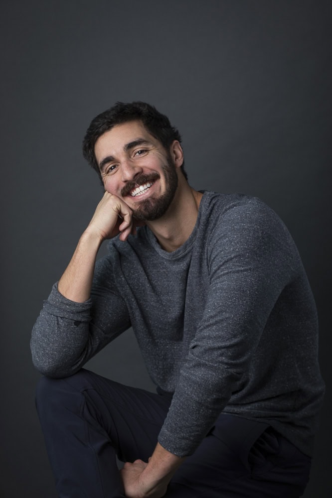 Confident man in professional headshot for branding website, smiling and relaxed.