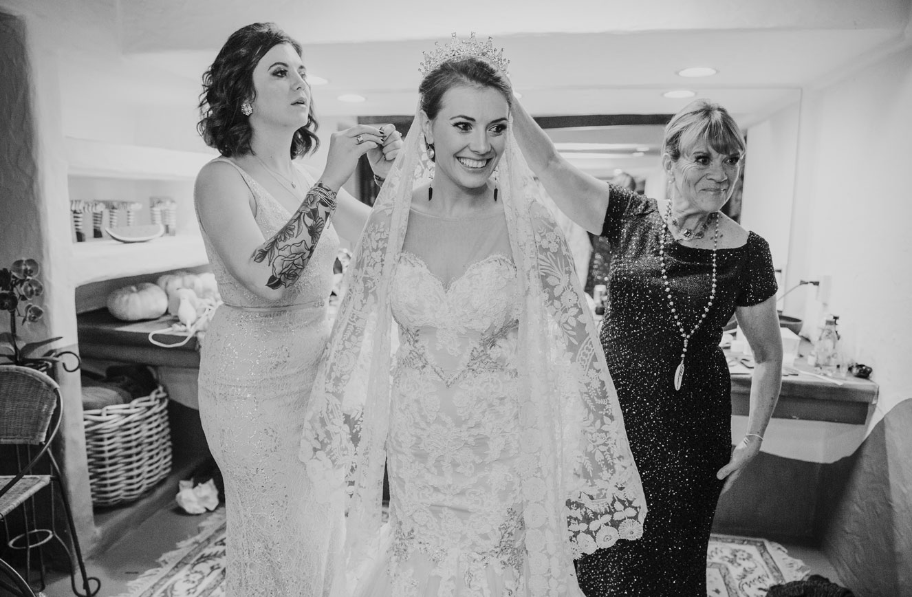 Bridesmaids and mom helping the bride put on her dress at Holly Farms.