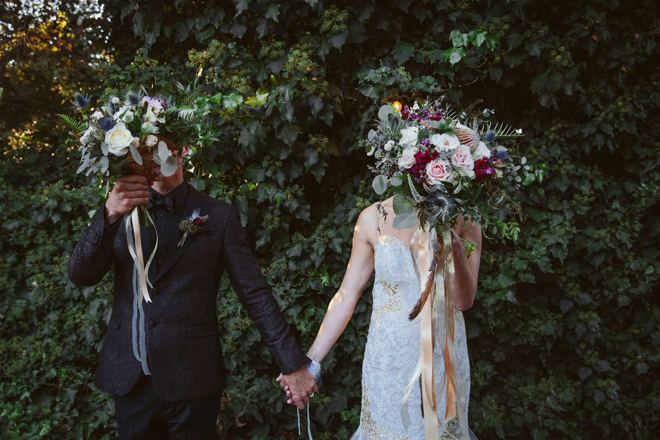 Bride and groom's being playful and covering their faces with bouquets at a Carmel Wedding.