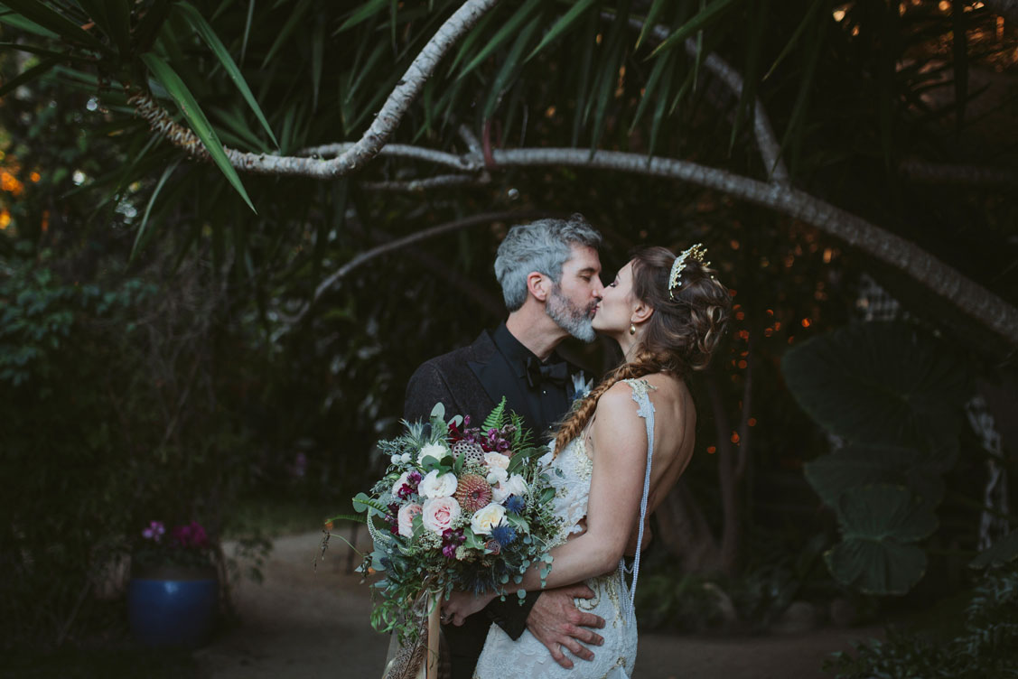 Bride and groom give a celebratory kiss among the lush gardens in Holly Farms.