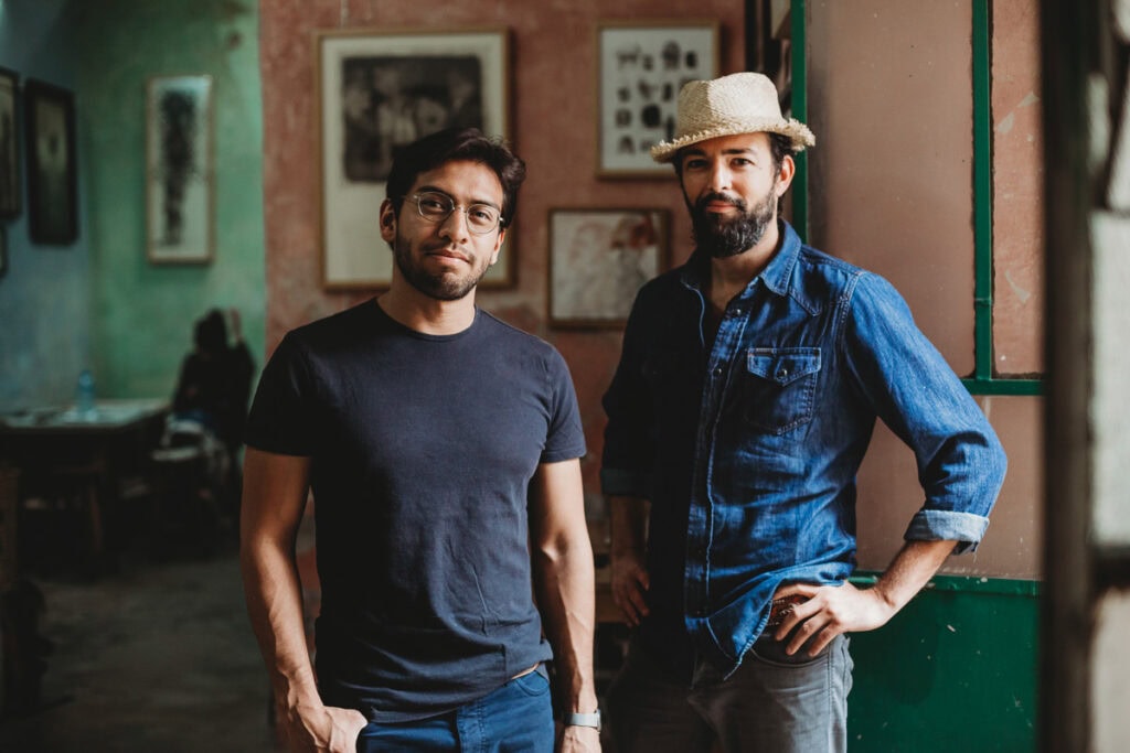 Two men in casual attire posing in an art gallery for branding photography.