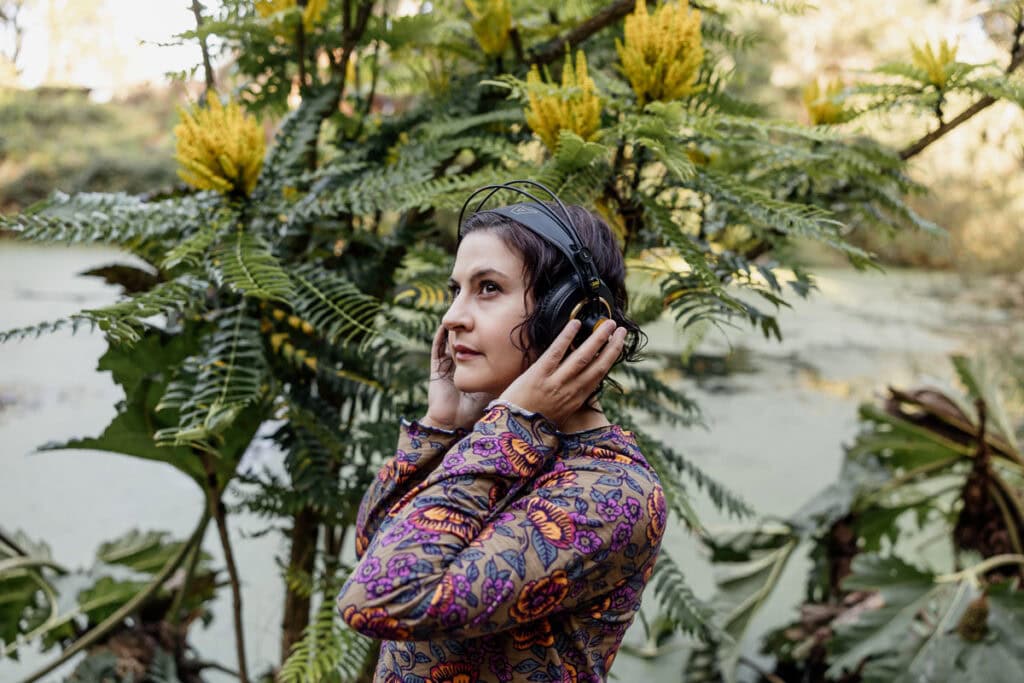 Woman with headphones outdoors, working as a sound designer and musician.