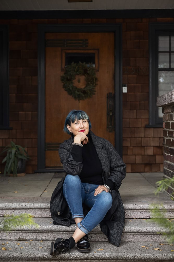 Woman sitting on front steps of a brick house, promoting new branding website.