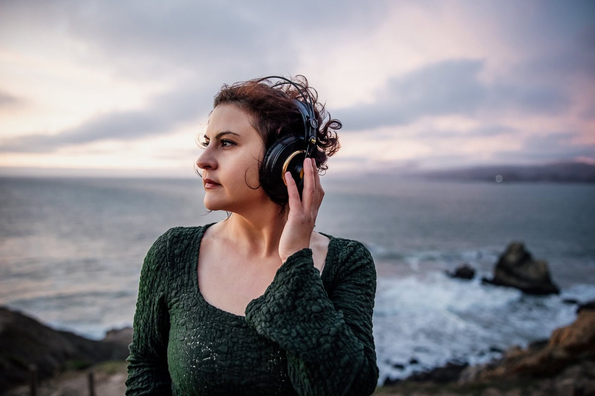 Woman with headphones outdoors by the sea, sound engineer and musician.