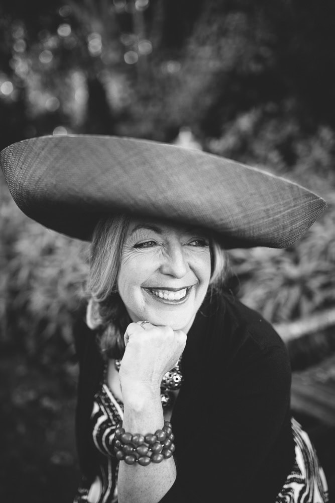 Elegant woman wearing a large hat, smiling in a natural outdoor setting.- San Francisco Branding Photography