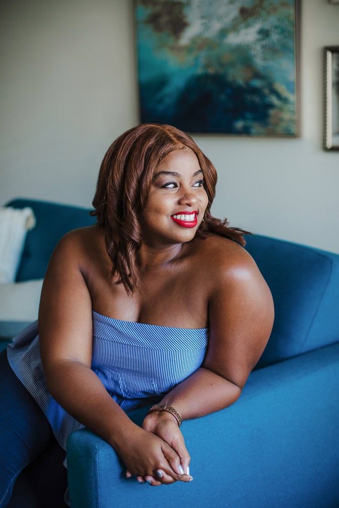 Confident woman with red hair smiling on blue sofa in modern home.
