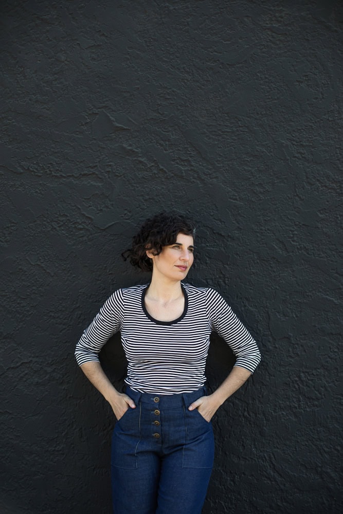 Woman in striped top standing against dark textured wall for branding photoshoot.