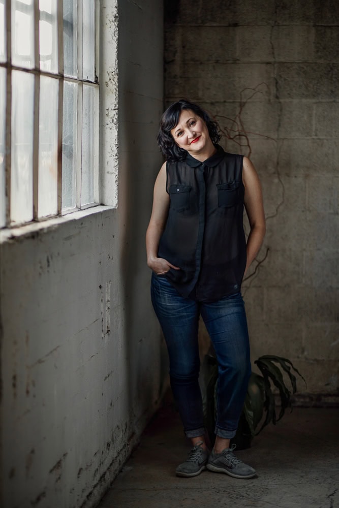 Elegant portrait of a woman in casual clothing at an industrial-style window setting for branding ph.