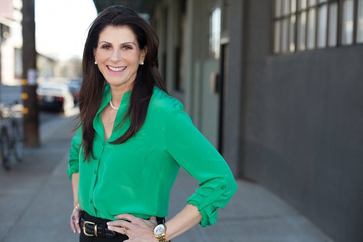 Confident businesswoman in green blouse smiling outdoors for branding site.