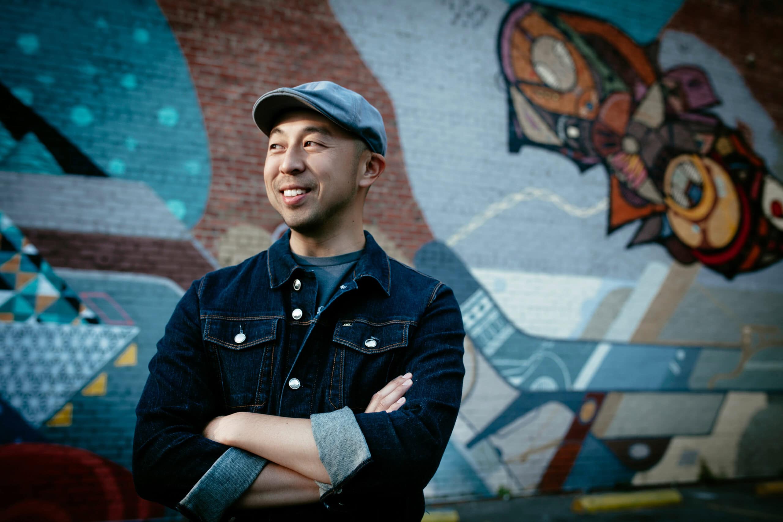 DJ standing in front of vibrant graffiti wall . Branding photography for creatives in Oakland, California.