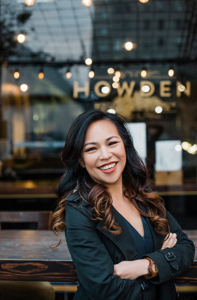 Woman smiling outdoors with a blurred background of a modern building and warm lighting -Bay Area Branding Photography