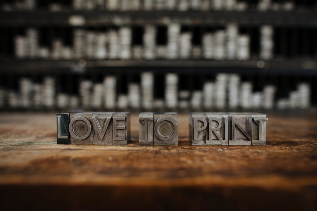 Wooden letter blocks spelling "Love to Print" on a rustic surface. San Francisco Center for the Book Branding Photography