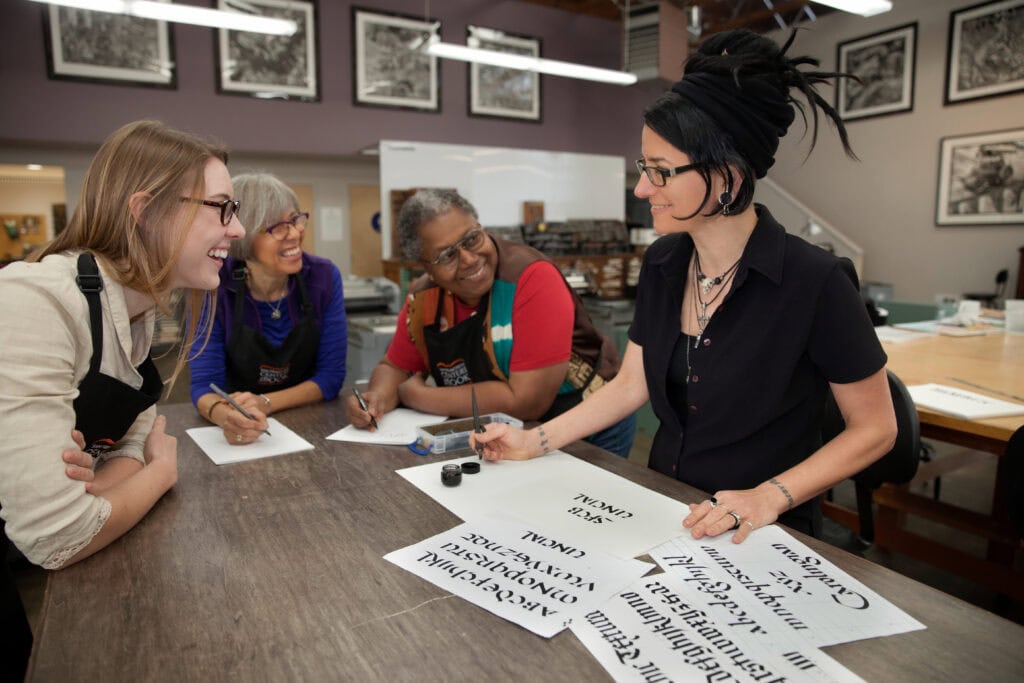 Creative calligraphy workshop with diverse women in a classroom setting. Branding photography for San Francisco for the Book