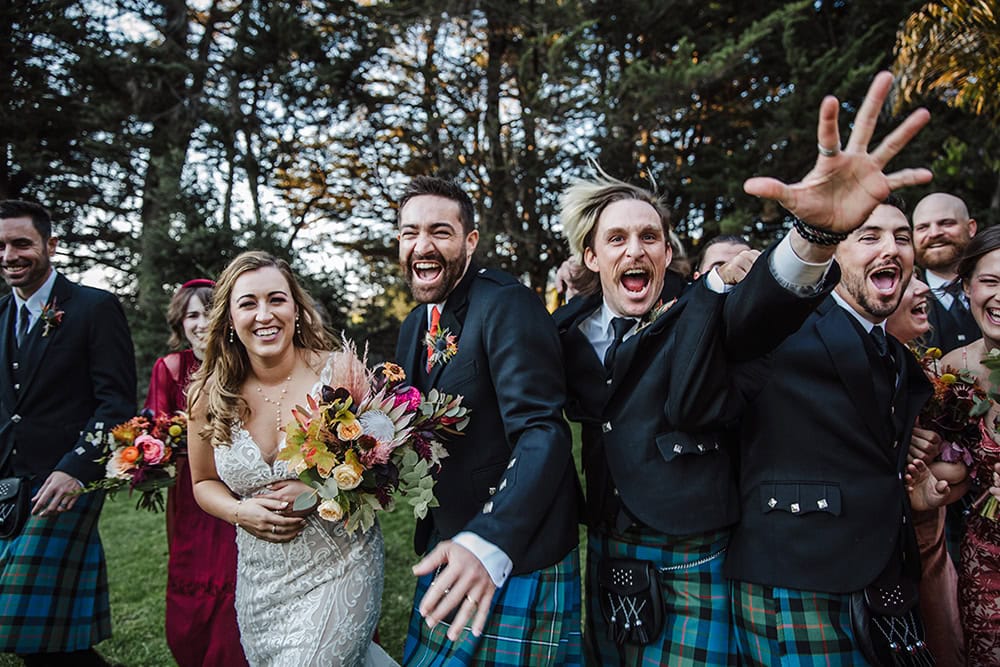 Vibrant wedding celebration with happy guests, colorful attire, and joyful expressions outdoors.