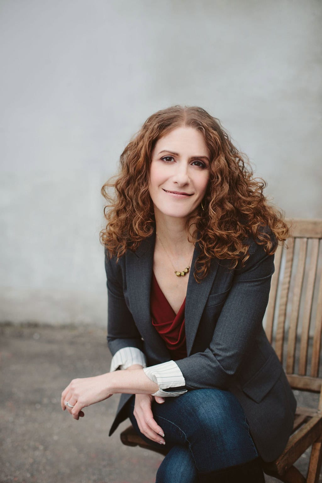 Confident businesswoman with curly hair sitting on a wooden bench, promoting new branding site.