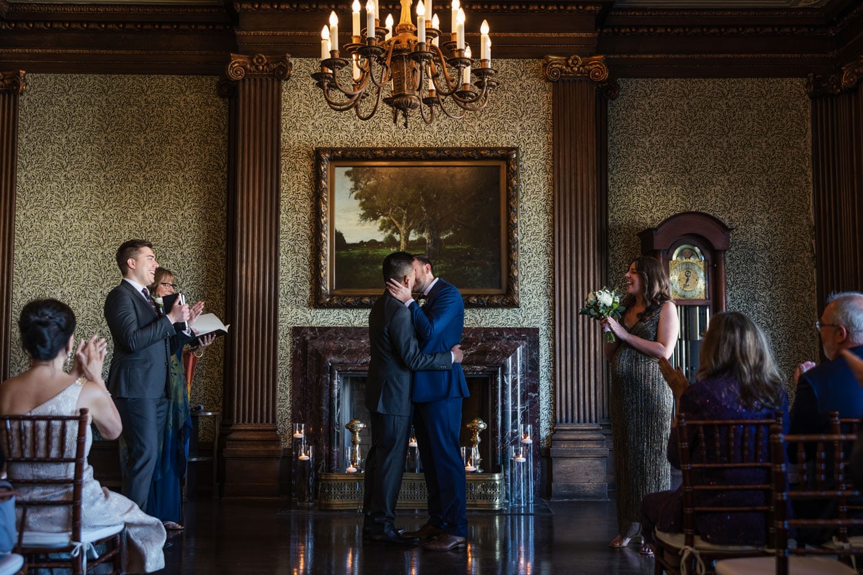 Wedding ceremony with couple exchanging vows in elegant historic venue.