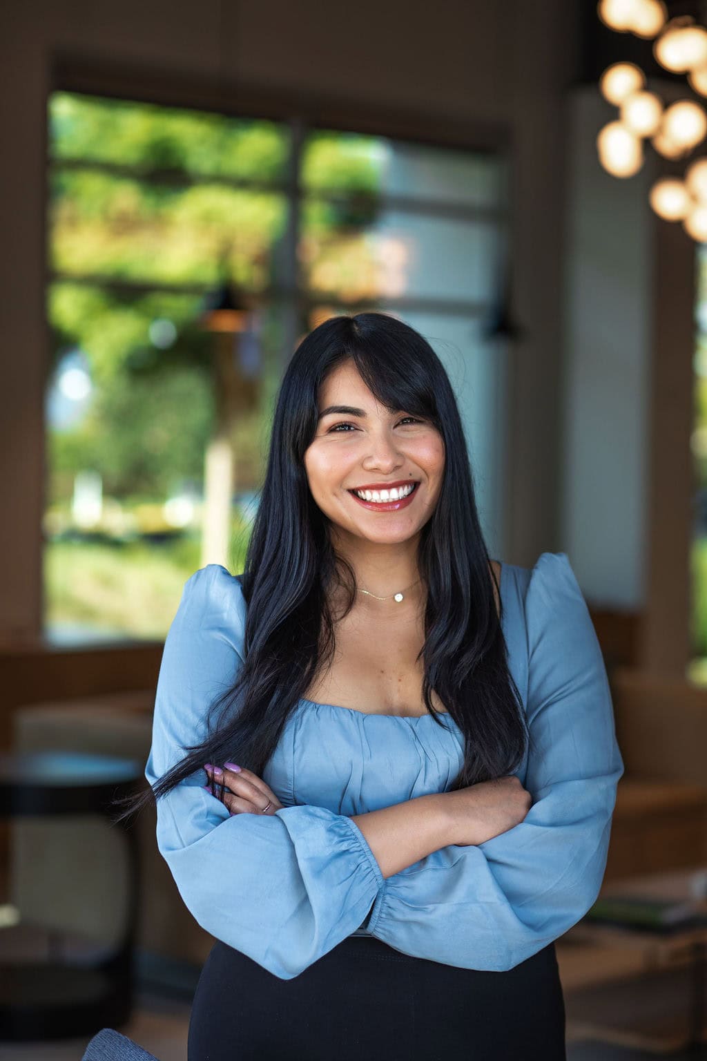 Professional woman smiling with arms crossed in modern office setting.