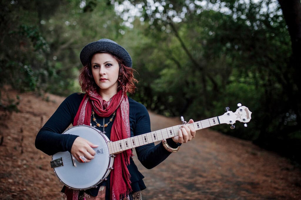 Woman holding banjo outdoors in forest, showcasing new branding photography for professional website.