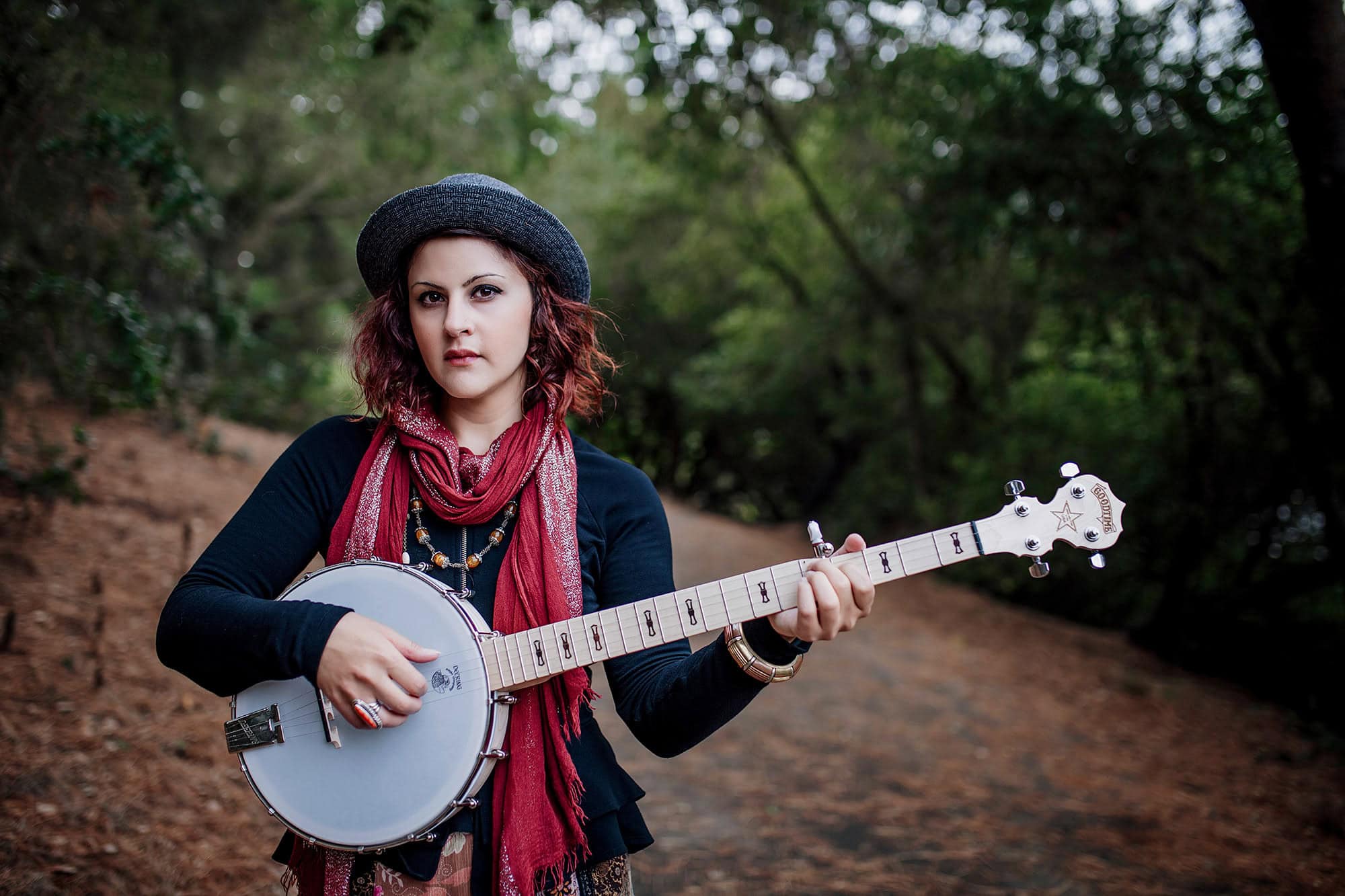 Woman holding banjo outdoors in forest, showcasing new branding photography for professional website.