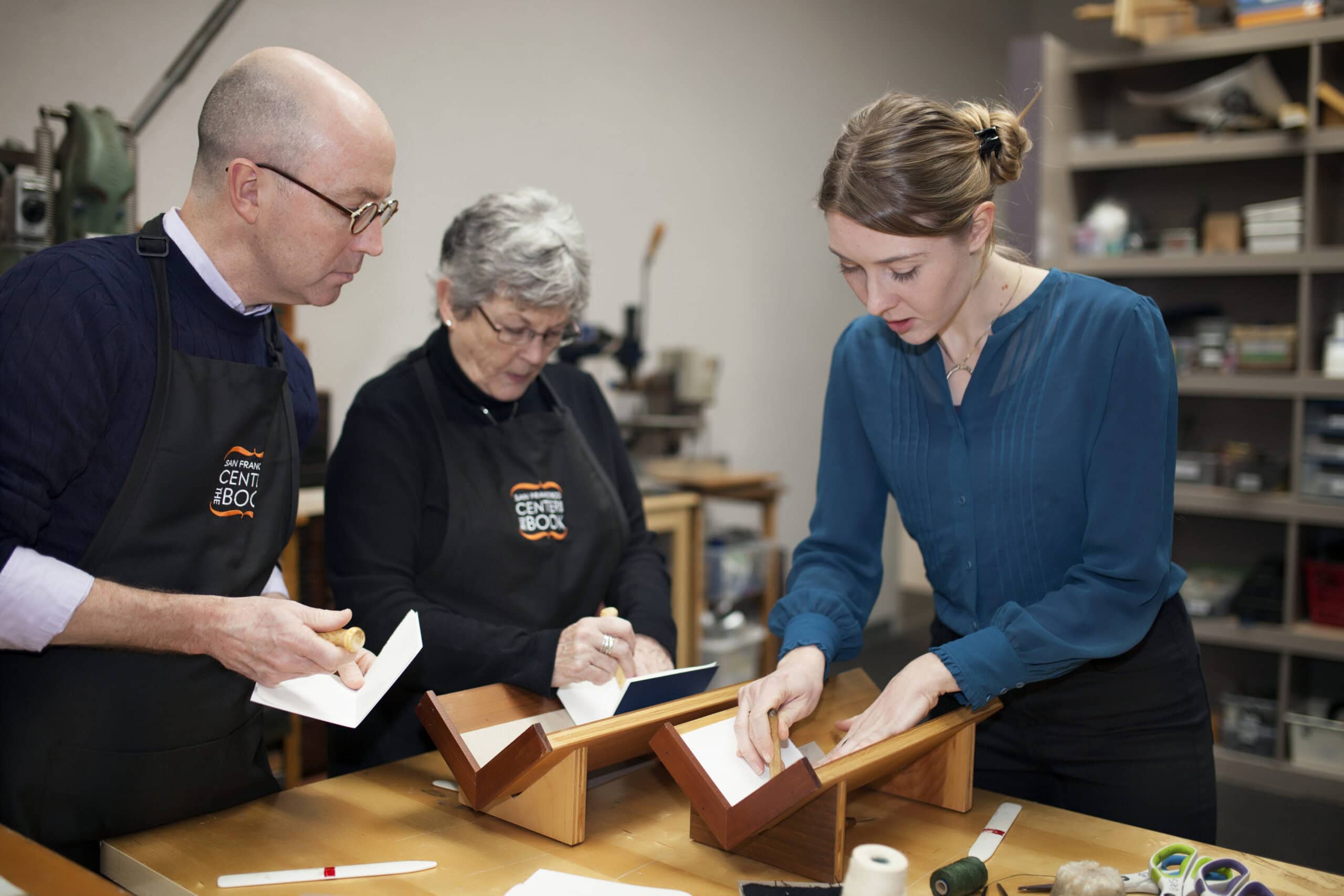 Three artisans working on woodworking projects in a workshop, focusing on craftsmanship and design.