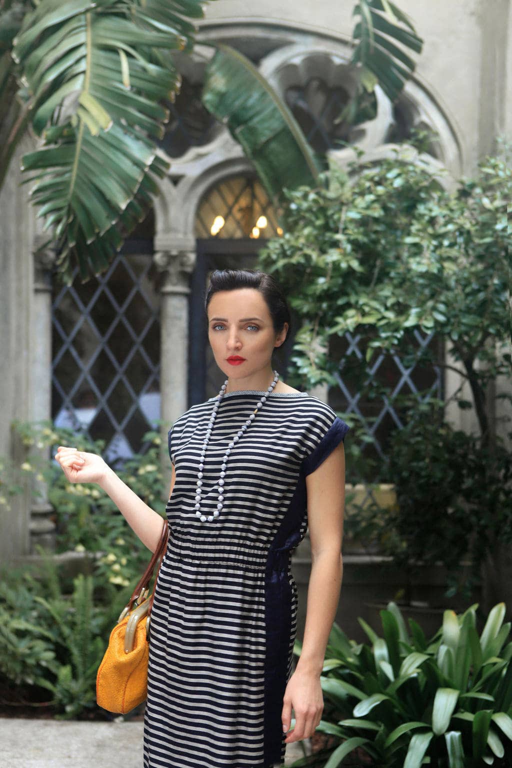 Modern woman in striped dress in lush garden setting.