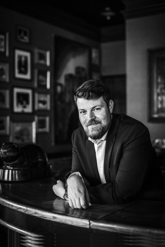 Man sitting at bar counter in a stylish, modern bar setting, black and white photography.