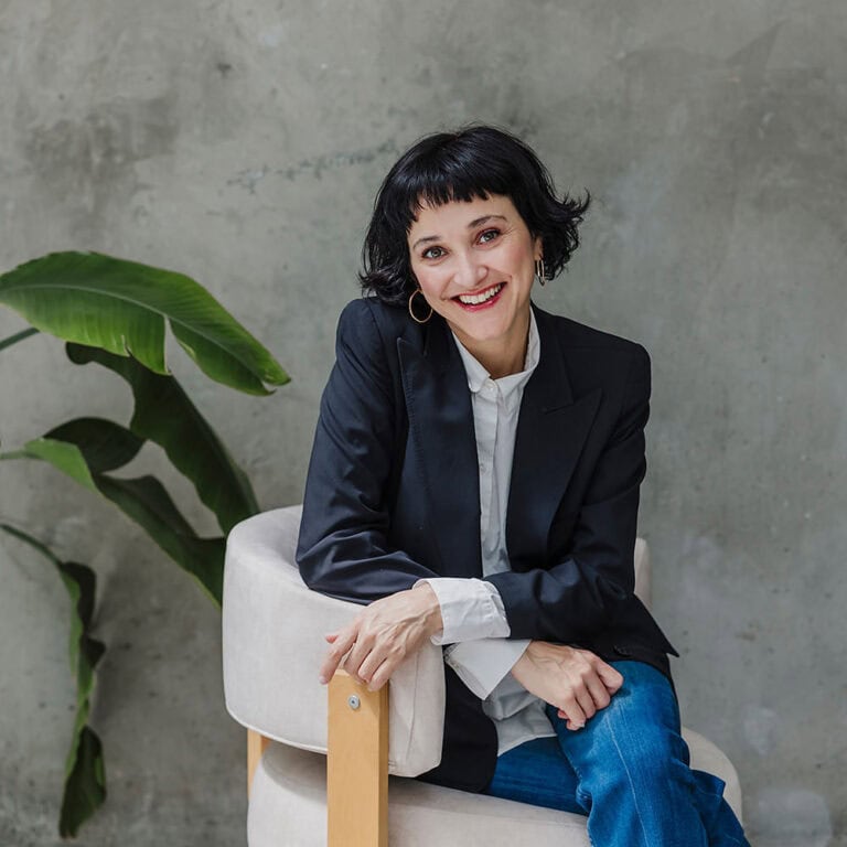 Confident businesswoman in professional attire smiling in modern office.